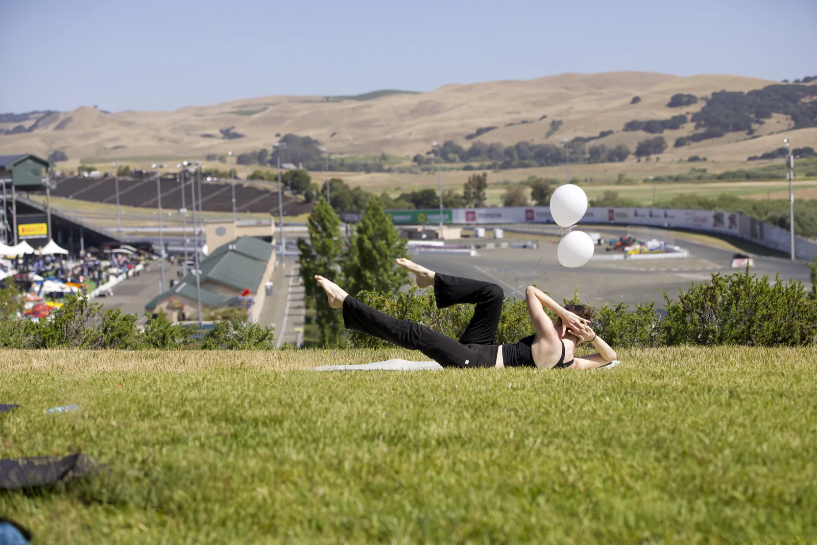 Outdoor corporate Pilates class on grass near a racetrack